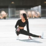 Mulher usando look esportivo preto e segurando tênis, inspiração para look athleisure.