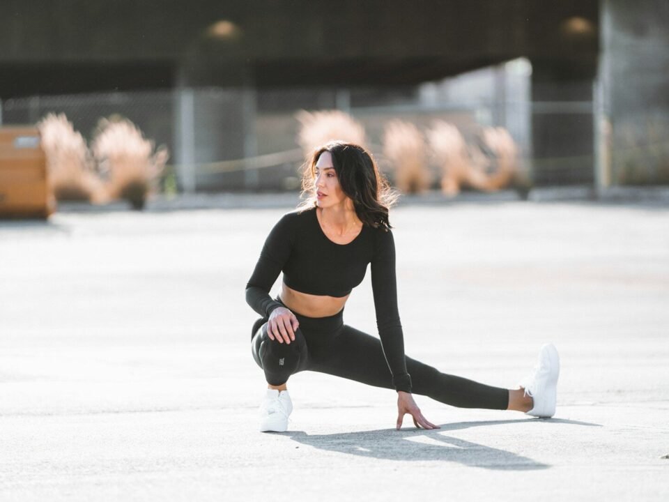 Mulher usando look esportivo preto e segurando tênis, inspiração para look athleisure.